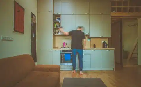 man facing on gray wooden cabinet picking container